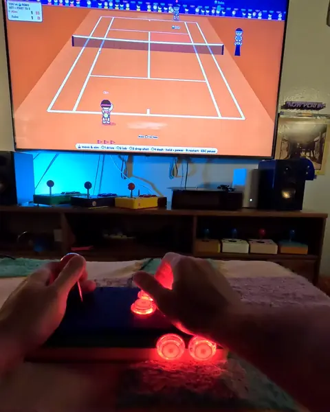 A tennis game on a living-room TV, and two hands on an arcade station whose buttons glow red.